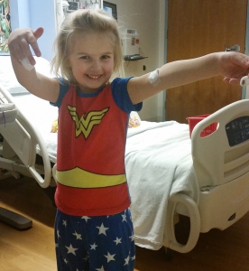 Karis wearing Wonder Woman pajamas in her hospital room.