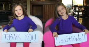 Arielle and Joelle holding "thank you HealthWell" signs.