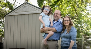 HealthWell grant recipient Aliza with her mom and dad in the backyard near the shed.