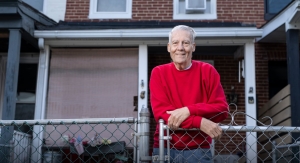 HealthWell grant recipient Robert in front of his house with his arm resting on the chain link fence.