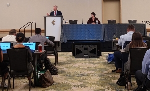 Charles Collins, President of Healthcare Stakeholder Solutions LLC, at a podium speaking to the crowd at the 10th Annual National Association of Specialty Pharmacy conference.